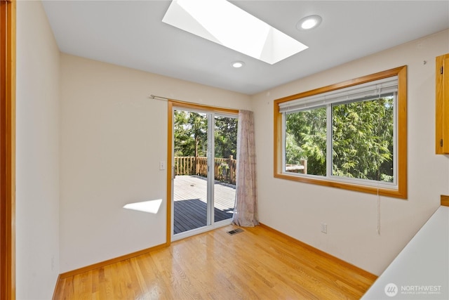 doorway with a skylight, light wood-style floors, recessed lighting, and baseboards