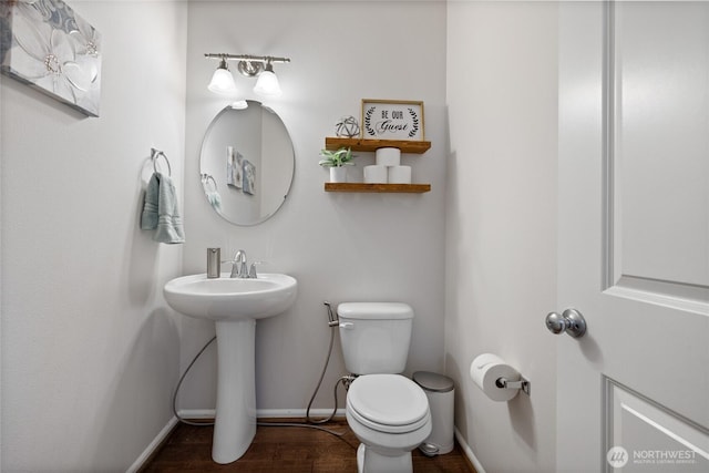 bathroom with toilet, baseboards, wood finished floors, and a sink