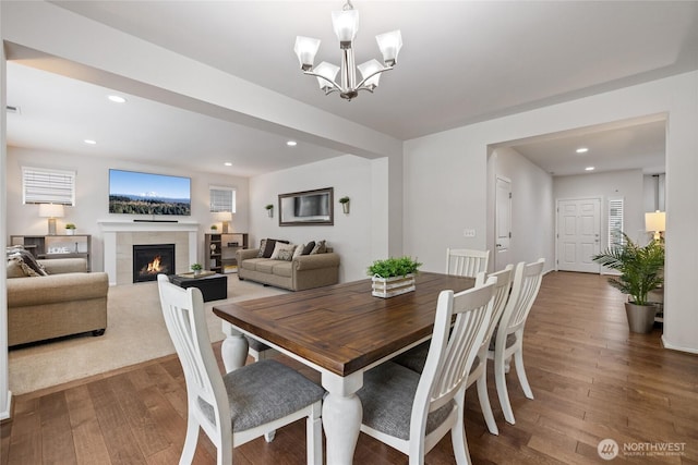 dining space with hardwood / wood-style floors, a chandelier, a tiled fireplace, and recessed lighting