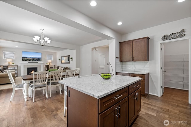 kitchen featuring open floor plan, dark wood-style floors, a chandelier, tasteful backsplash, and decorative light fixtures