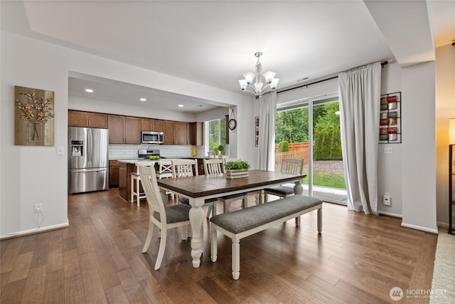 dining space with a chandelier, dark wood-type flooring, recessed lighting, and baseboards