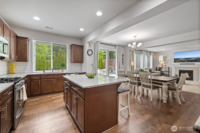 kitchen featuring appliances with stainless steel finishes, open floor plan, a breakfast bar, backsplash, and a center island