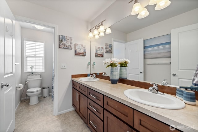 bathroom featuring double vanity, baseboards, and toilet