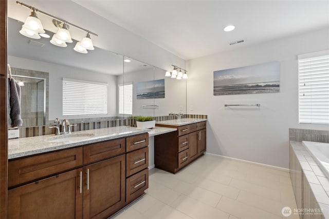 full bath with two vanities, a shower stall, tiled bath, tile patterned floors, and baseboards