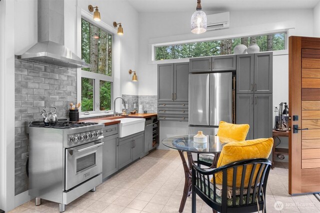 22717 Briarwood Ct SE, Yelm, WA 98597 - kitchen with stainless steel appliances, wall chimney exhaust hood, a sink, and plenty of natural light
