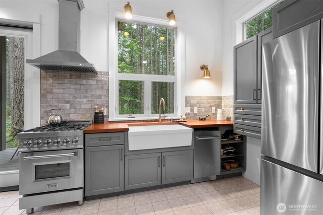 22717 Briarwood Ct SE, Yelm, WA 98597 - kitchen featuring appliances with stainless steel finishes, wood counters, wall chimney exhaust hood, and a sink
