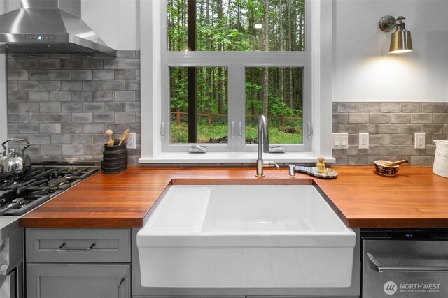 22717 Briarwood Ct SE, Yelm, WA 98597 - kitchen with wooden counters, wall chimney exhaust hood, a sink, stainless steel appliances, and gray cabinetry