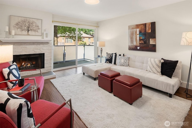living area with wood finished floors and a stone fireplace