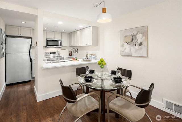 dining area featuring baseboards, dark wood finished floors, and recessed lighting