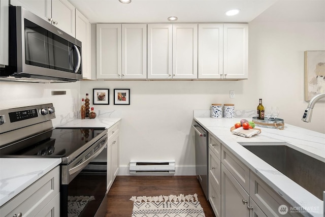 kitchen featuring stainless steel appliances, a sink, baseboard heating, light stone countertops, and white cabinets