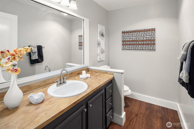 bathroom featuring wood finished floors, toilet, vanity, and baseboards