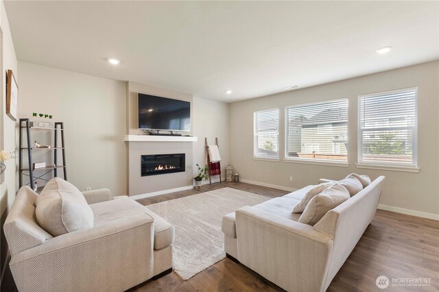 living area with wood finished floors, recessed lighting, baseboards, and a glass covered fireplace