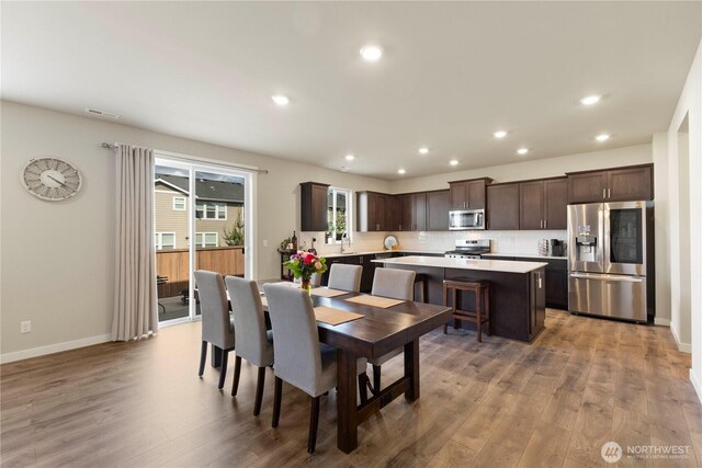 dining room with light wood-style floors, recessed lighting, and baseboards