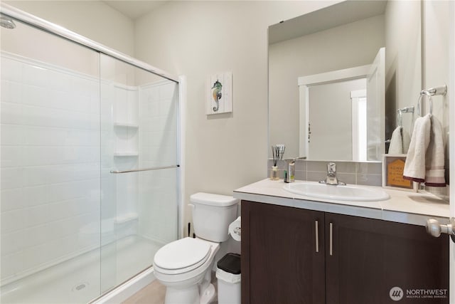 bathroom featuring tasteful backsplash, a shower stall, toilet, and vanity