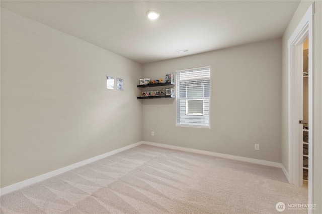 unfurnished room featuring light carpet and baseboards
