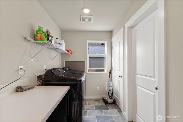 washroom featuring washing machine and clothes dryer, baseboards, and stone finish flooring