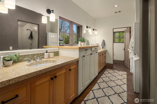 30404 44th Ave NW, Stanwood, WA 98292 - bathroom featuring decorative backsplash, stacked washer / drying machine, vanity, recessed lighting, and wood finished floors