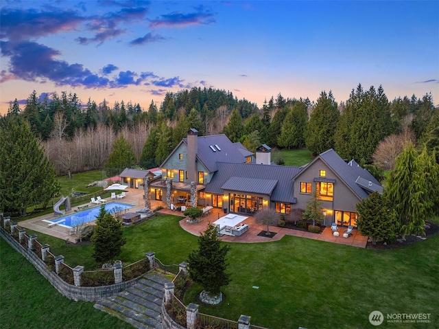 30404 44th Ave NW, Stanwood, WA 98292 - back of house at dusk featuring a patio, a chimney, a standing seam roof, and metal roof