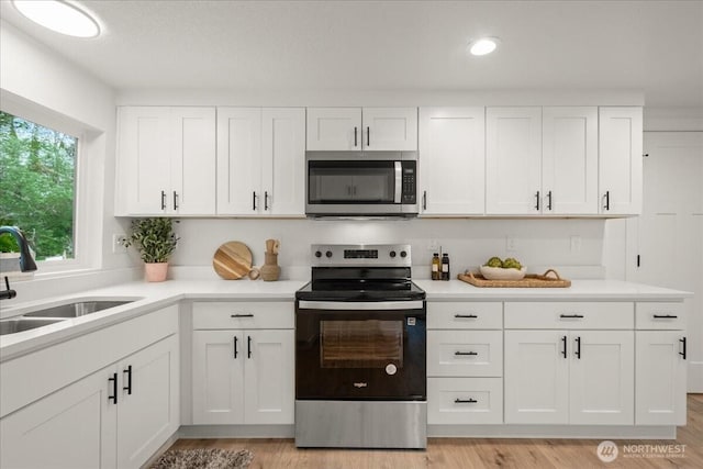 1405 33rd St, Seaview, WA 98644 - kitchen featuring appliances with stainless steel finishes, a sink, light countertops, white cabinetry, and light wood-style flooring