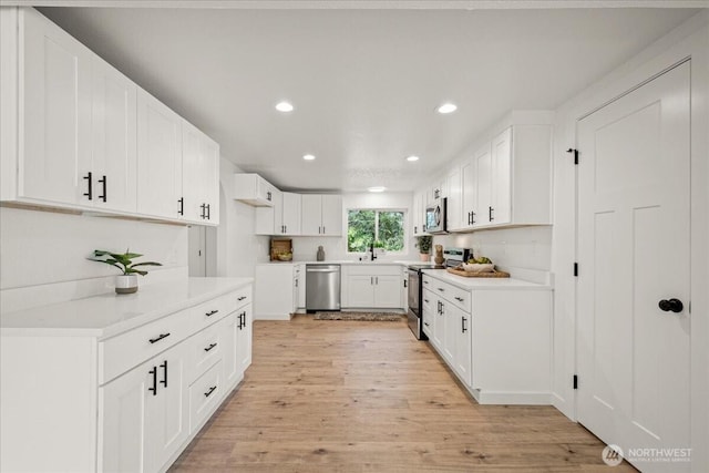 1405 33rd St, Seaview, WA 98644 - kitchen with stainless steel appliances, recessed lighting, light wood-style flooring, white cabinetry, and light countertops