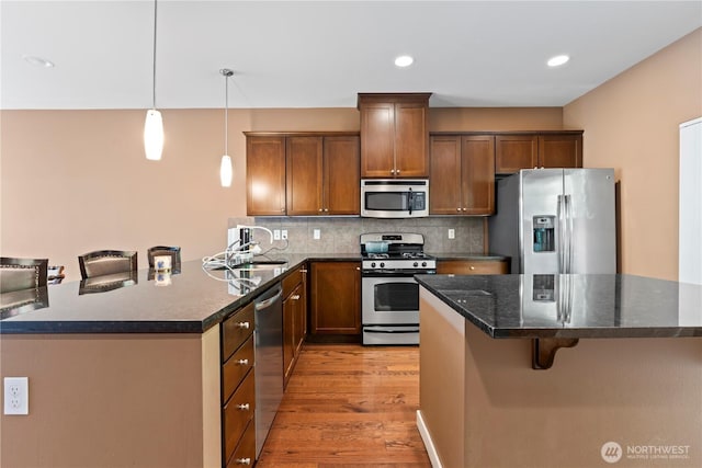 16404 1st Dr SE, Bothell, WA 98012 - kitchen with appliances with stainless steel finishes, a breakfast bar area, light wood-style flooring, backsplash, and decorative light fixtures