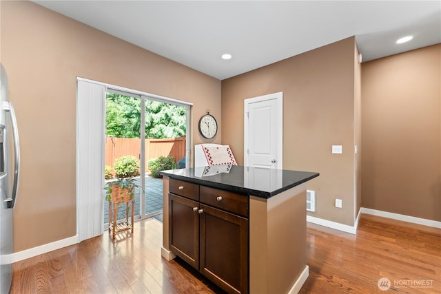 16404 1st Dr SE, Bothell, WA 98012 - kitchen with wood finished floors, baseboards, freestanding refrigerator, a kitchen island, and dark stone counters