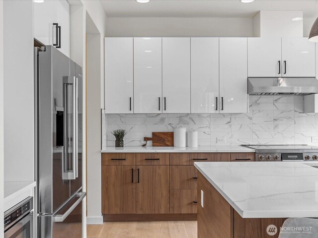 667 17th Ave NW, Issaquah, WA 98027 - kitchen featuring appliances with stainless steel finishes, under cabinet range hood, white cabinetry, tasteful backsplash, and recessed lighting