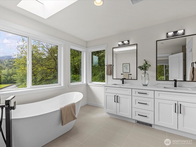 667 17th Ave NW, Issaquah, WA 98027 - full bath featuring a skylight, double vanity, a freestanding tub, baseboards, and tile patterned flooring