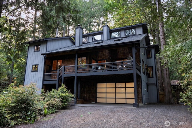 view of front facade with driveway, an attached garage, and a chimney