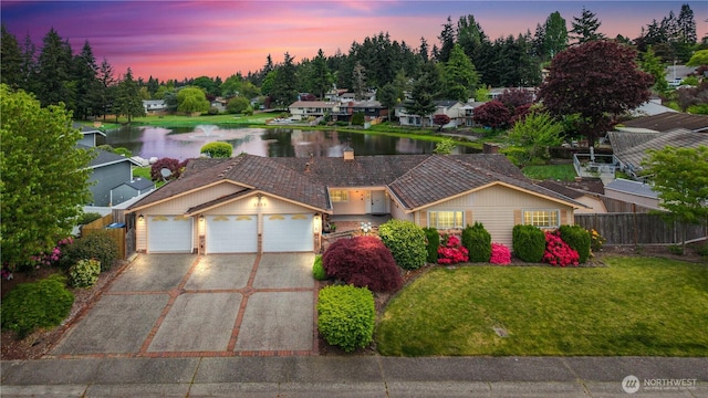 view of front of home with driveway, a water view, and an attached garage