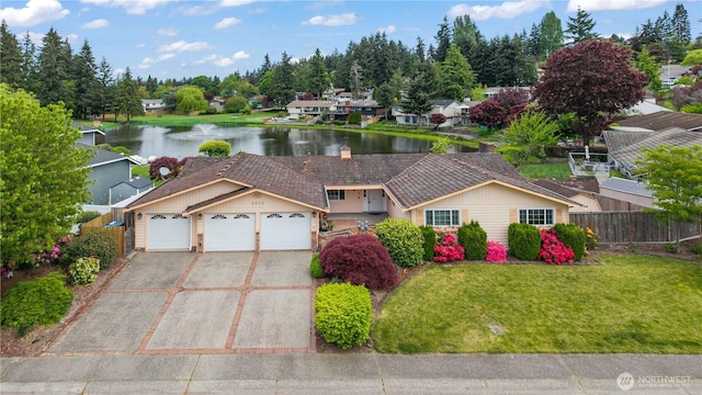 view of front of property with driveway, an attached garage, and a water view