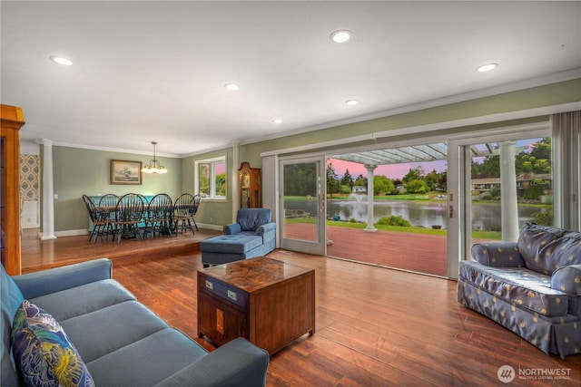 living area featuring ornamental molding, a water view, a chandelier, wood finished floors, and baseboards