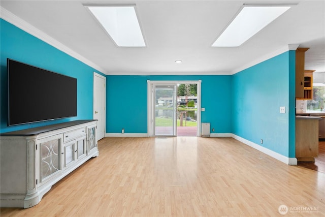 unfurnished living room featuring a skylight, ornamental molding, baseboards, and light wood-style flooring