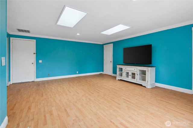 unfurnished living room featuring a skylight, ornamental molding, wood finished floors, baseboards, and recessed lighting