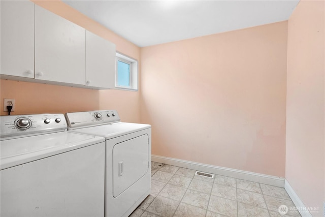 laundry room featuring baseboards, separate washer and dryer, and cabinet space