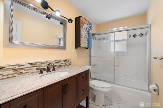 full bath with backsplash, toilet, vanity, tile patterned floors, and bath / shower combo with glass door