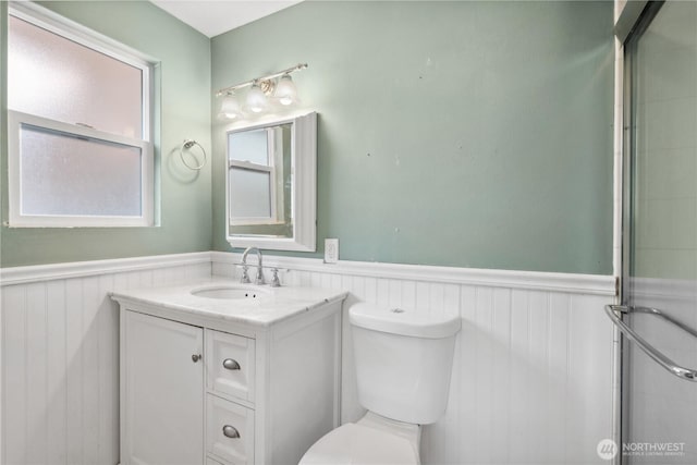 bathroom with a wainscoted wall, toilet, and vanity