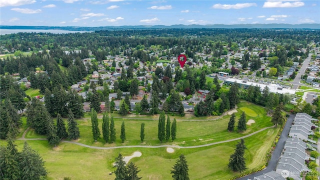 aerial view of property's location with a golf course and a nearby body of water