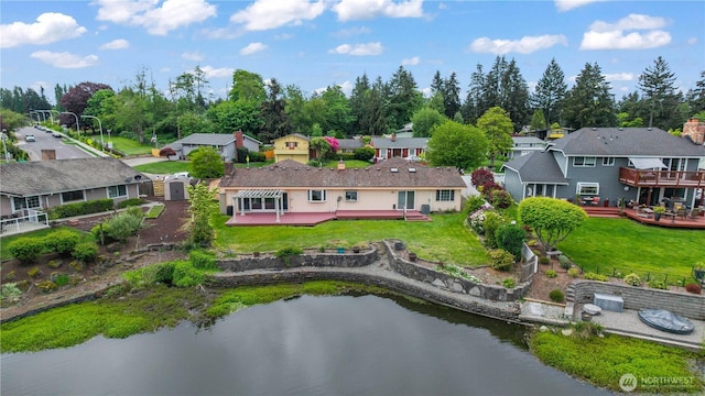 back of property with a deck with water view, a yard, and a residential view
