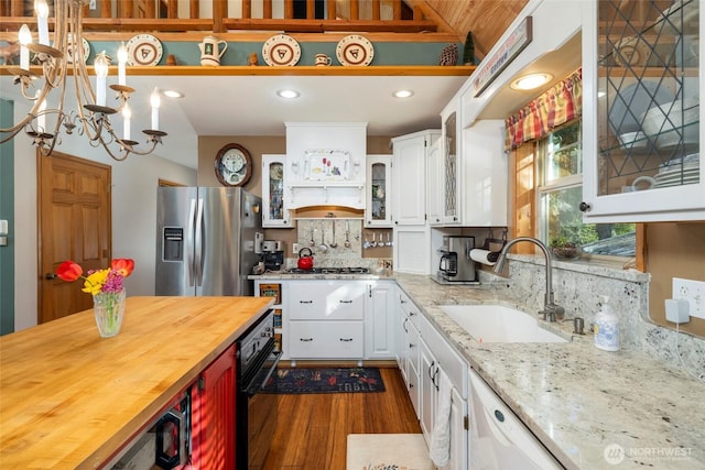 kitchen with stainless steel appliances, a sink, dark wood-type flooring, butcher block counters, and white cabinetry