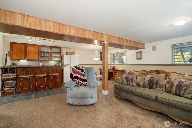 living room featuring rail lighting, dark colored carpet, dark tile patterned flooring, and bar