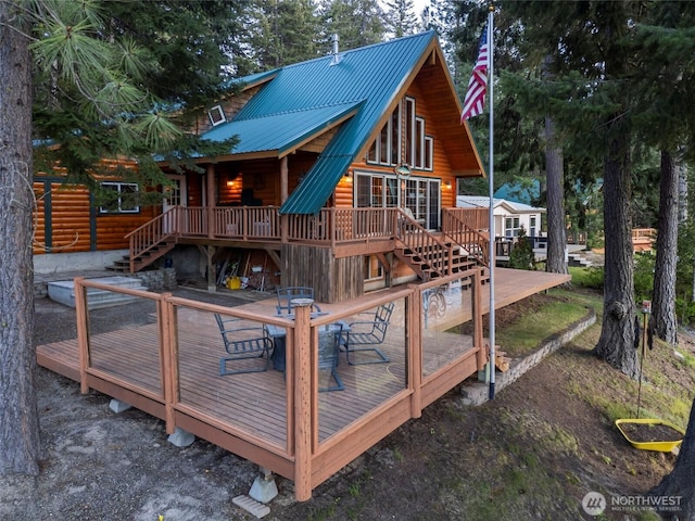 back of property with a deck, faux log siding, stairs, and metal roof