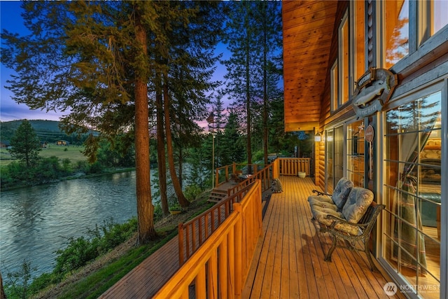 deck at dusk featuring a water view