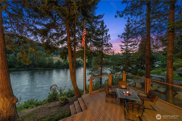 deck at dusk featuring a water view and a fire pit