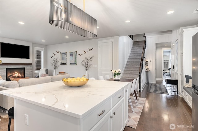 kitchen featuring a kitchen island, recessed lighting, white cabinetry, dark wood-style floors, and light stone counters