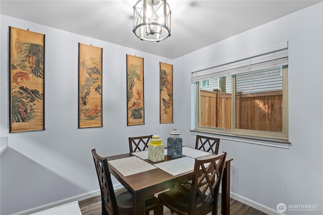 dining space featuring baseboards, wood finished floors, and a chandelier