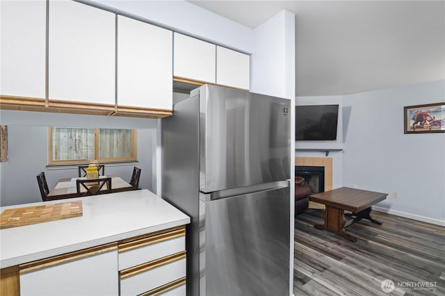 kitchen featuring freestanding refrigerator, white cabinetry, light countertops, wood finished floors, and a fireplace