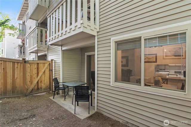 view of side of home featuring fence, a patio area, and a balcony