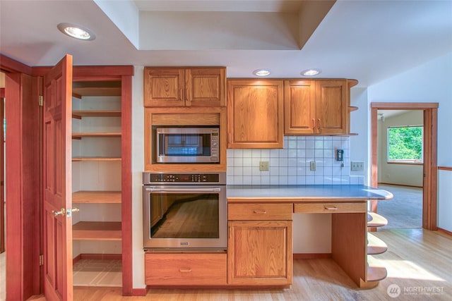 55 Langell Ln, Orcas Island, WA 98245 - kitchen featuring stainless steel appliances, light wood-style flooring, tasteful backsplash, brown cabinets, and light countertops