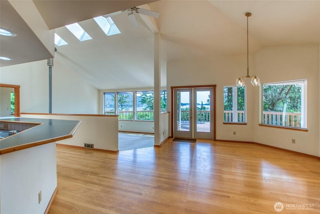 55 Langell Ln, Orcas Island, WA 98245 - unfurnished living room with light wood-type flooring, high vaulted ceiling, a skylight, baseboards, and a chandelier